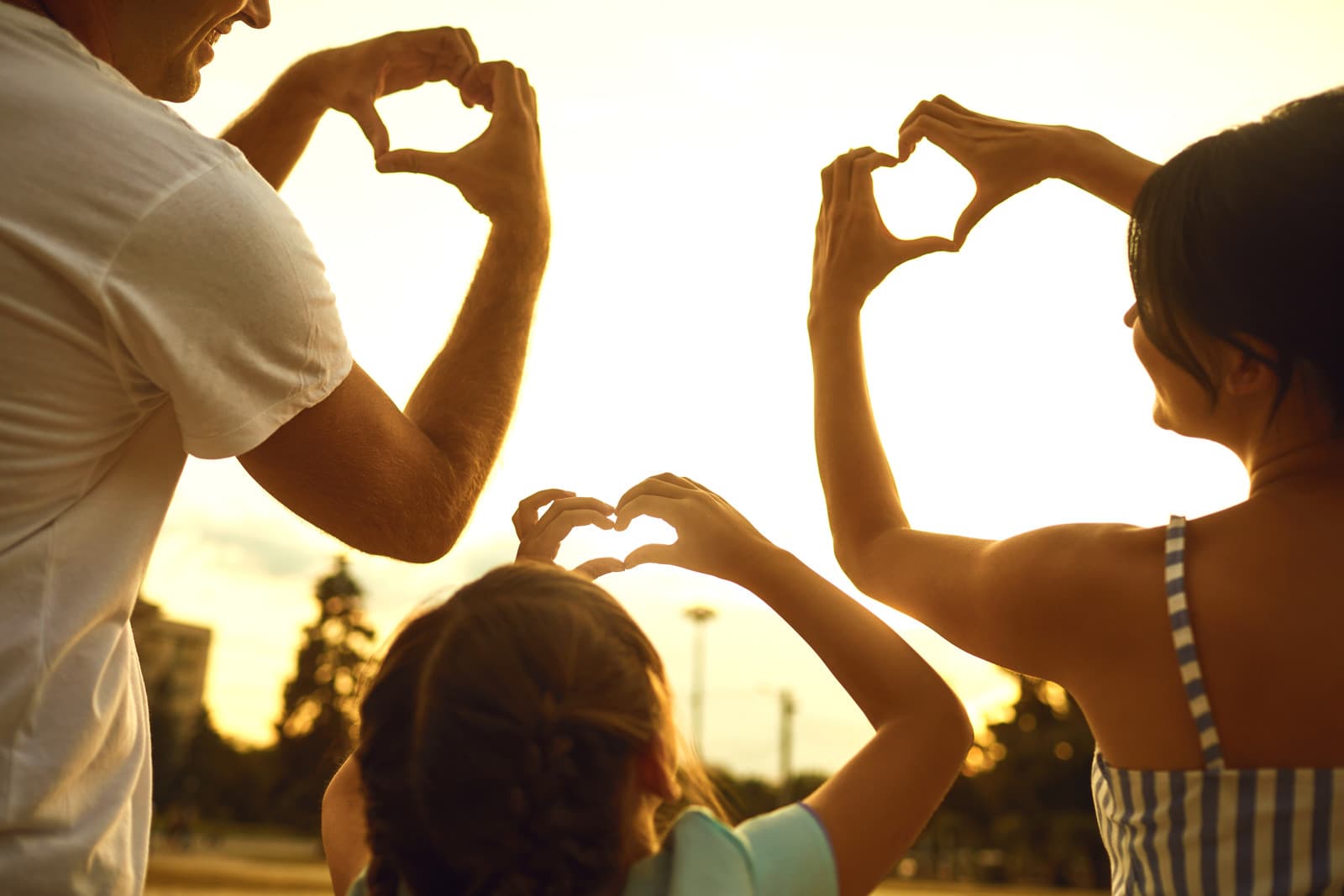 Family making heart shapes at sunset